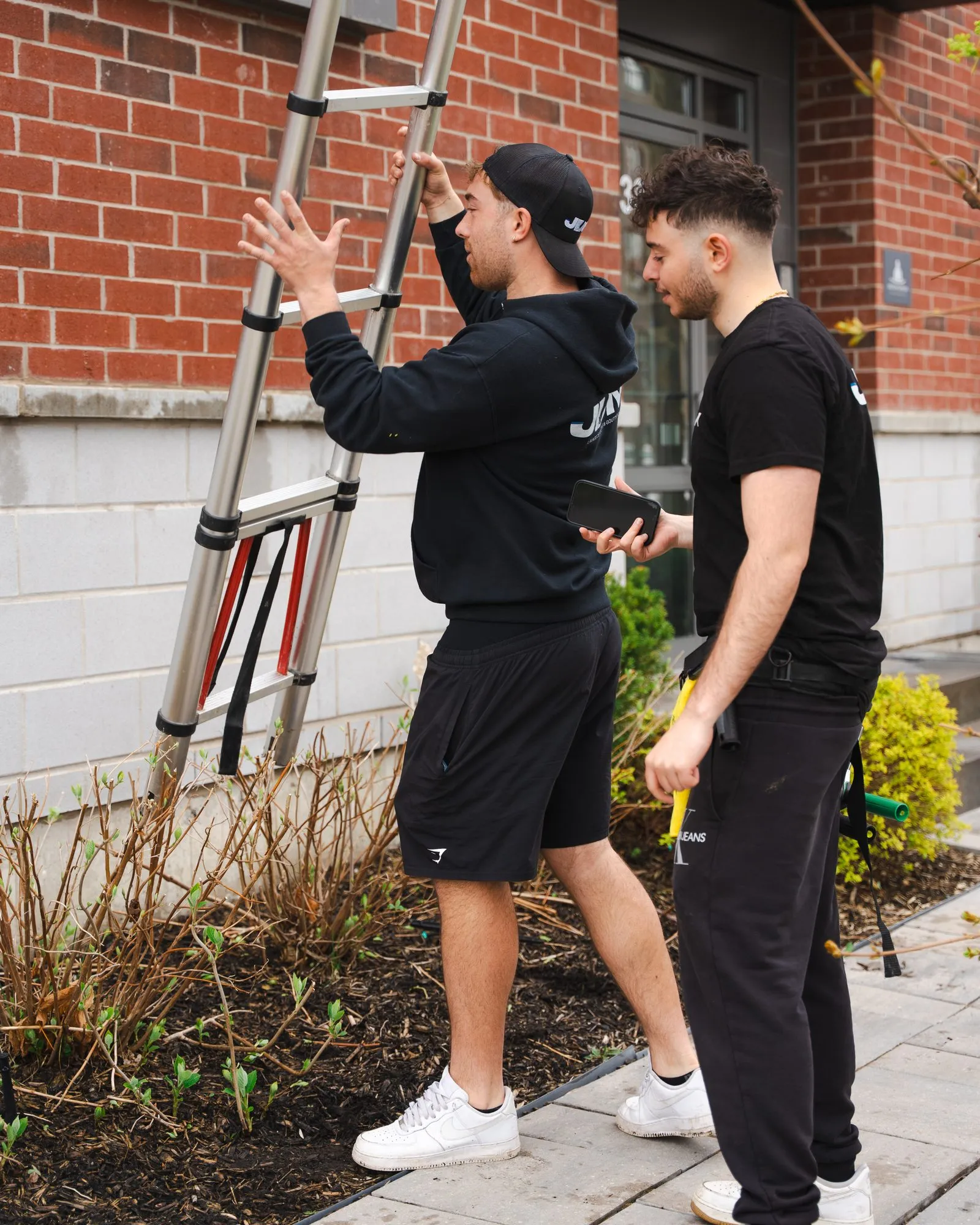 A ladder rests against a brick building so the Lavage JDM crew can reach the gutters.